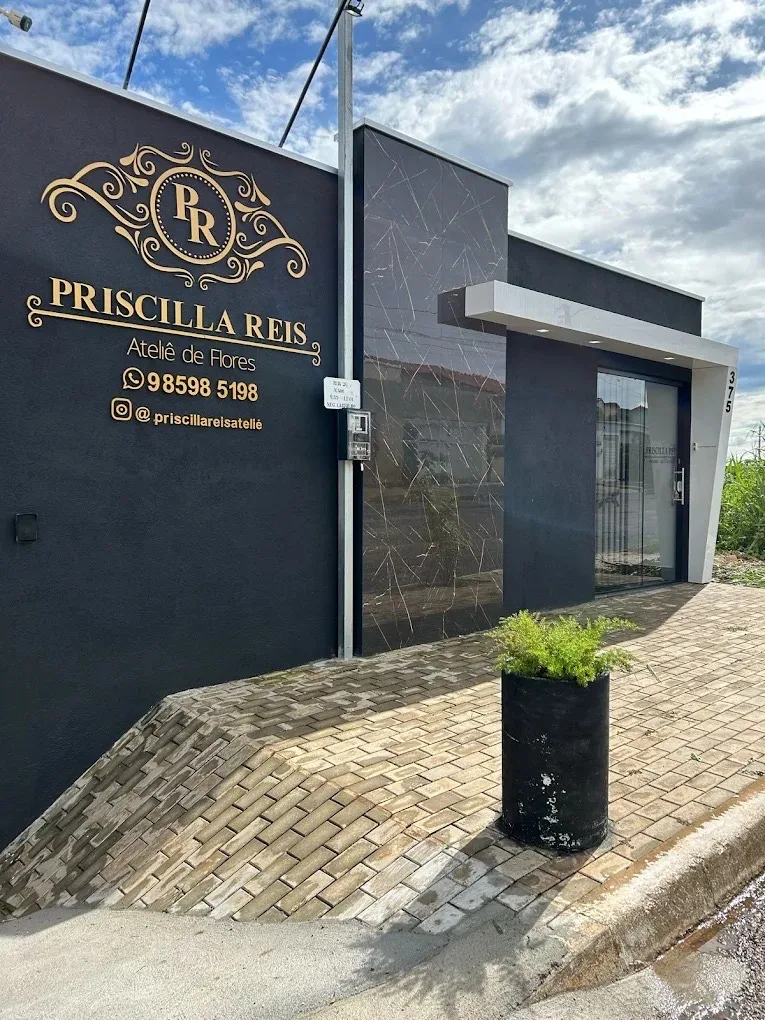 Fachada do ateliê Priscilla Reis, com a marca dourada na parede escura e a entrada de vidro.